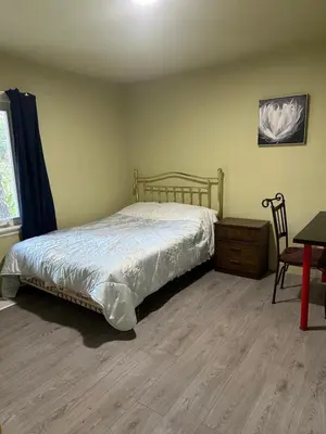 a bedroom with a bed and a table and a chair at Tom home in Toronto