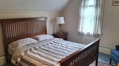 a bedroom with a bed and a chair and a window at Century House on Quarter acre lot in Acton