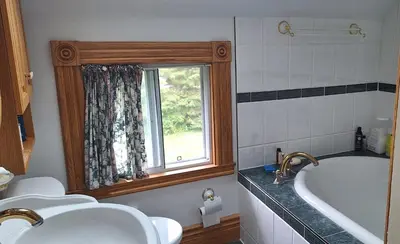 a bathroom with a tub and a sink and a window at Century House on Quarter acre lot in Acton