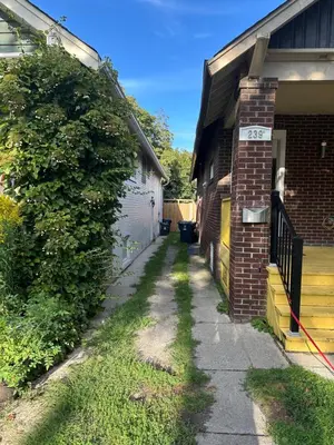 a sidewalk next to a house with a hedge at Toronto Upper Beaches Apartment in Toronto