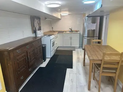 a kitchen with white appliances and a wooden table at Toronto Upper Beaches Apartment in Toronto