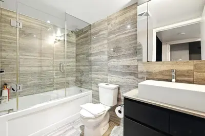 a bathroom with a toilet and a tub and a sink at Stylish DT Condo with Vanity Mirror, Free Parking! in Toronto