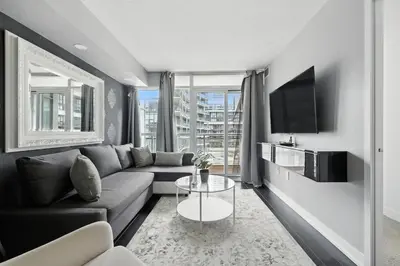 a living room with a couch and a tv at Stylish DT Condo with Vanity Mirror, Free Parking! in Toronto
