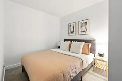 a bedroom with a large bed with white walls at Stylish DT Condo with Vanity Mirror, Free Parking! in Toronto