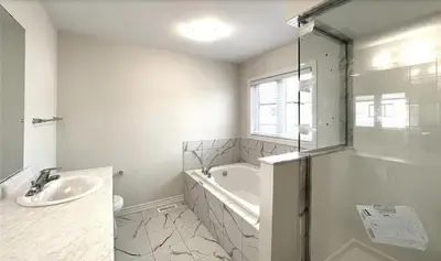 a white bathroom with a tub and a sink at Two Adjacent Modern Homes in West Niagara Sleep 16 in Thorold