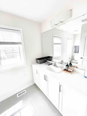 a white bathroom with a sink and a mirror at Two Adjacent Modern Homes in West Niagara Sleep 16 in Thorold