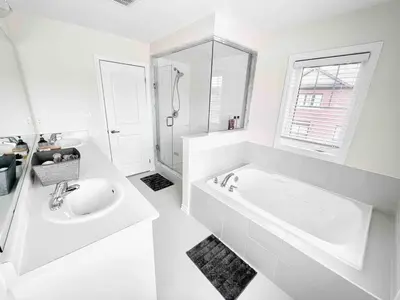 a white bathroom with a tub and a sink at Two Adjacent Modern Homes in West Niagara Sleep 16 in Thorold