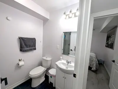 a white bathroom with a toilet and a sink at Bright & New 2 Beds Near Subway in Toronto
