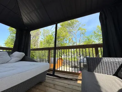 a bedroom with a bed and a balcony with a view at Hot Tub BANYA Sauna True Cottage experience in Innisfil