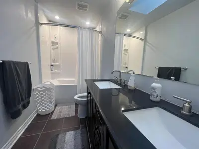 a bathroom with two sinks and a toilet and a mirror at Hot Tub BANYA Sauna True Cottage experience in Innisfil