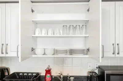 a kitchen with white cabinets and plates and a sink at SkyView 2BR Plus Den Stunning Views Steps to SQ1 Mall in Mississauga