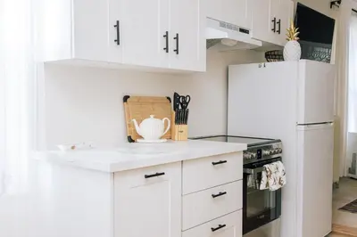 a kitchen with white cabinets and a white refrigerator at Dundas and Brock Suitel in Toronto