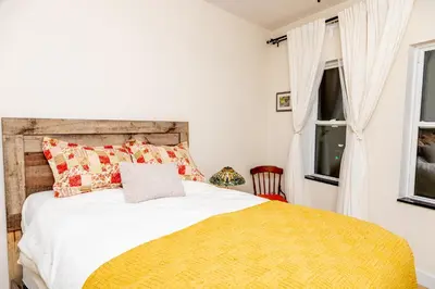 a bedroom with a bed with a yellow blanket and a window at Dundas and Brock Suitel in Toronto