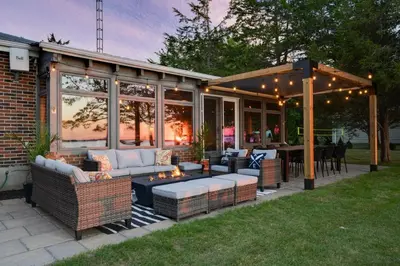 a screened in patio with couches and a table at Waterfront Casa in wine County with SAUNA and HOT TUB in Demorestville