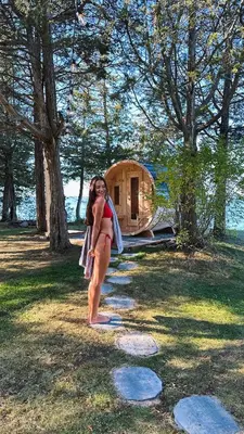 a woman in a bikini standing in front of a house at Waterfront Casa in wine County with SAUNA and HOT TUB in Demorestville