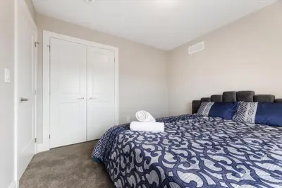 a bedroom with a bed with a blue and white comforter at Relaxing Retreat Office, Patio, Nature and Netflix in Colborne