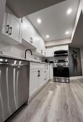 a kitchen with white cabinets and stainless steel appliances at Modern Suite in Etobicoke - Near Airport & Downtown! in Toronto