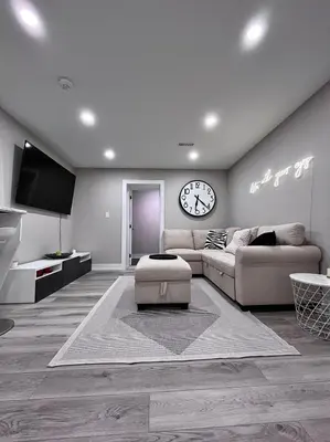 a living room with a couch and a clock on the wall at Modern Suite in Etobicoke - Near Airport & Downtown! in Toronto