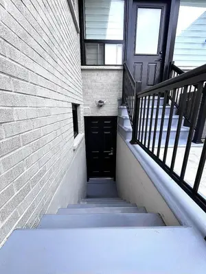 a stairway with a black door and a brick wall at Modern Suite in Etobicoke - Near Airport & Downtown! in Toronto