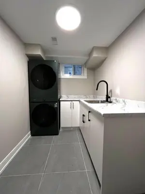 a kitchen with a black washer and dryer in it at Modern Suite in Etobicoke - Near Airport & Downtown! in Toronto