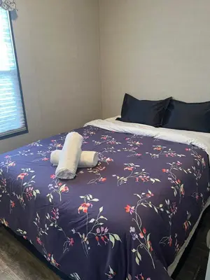 a bed with a blue blanket with flowers on it at Cottage on Niagara on the Lake in Niagara on the Lake