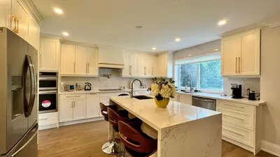 a kitchen with white cabinets and a kitchen island with flowers on it at Luxury 4BR Retreat with Pool, Piano, Spa & Games in Mississauga
