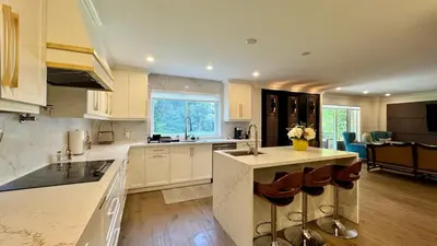 a kitchen with white cabinets and a island with a sink at Luxury 4BR Retreat with Pool, Piano, Spa & Games in Mississauga
