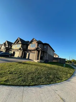 a house with a grassy yard in front of a street at Entire Home in Niagara Region, 6 bedrooms, 5 baths with a game room, arcades in Thorold