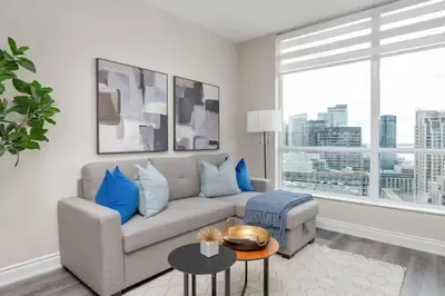 a living room with a couch and a large window at Stylish Fort York Condo w Patio Prime Location in Toronto