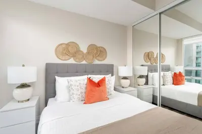 a bedroom with two beds with orange pillows and mirrors at Stylish Fort York Condo w Patio Prime Location in Toronto