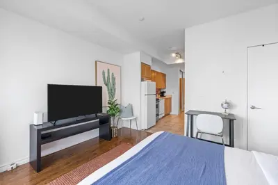 a bedroom with a bed and a flat screen tv at Chic Fort York Studio Cozy Retreat in Downtown in Toronto