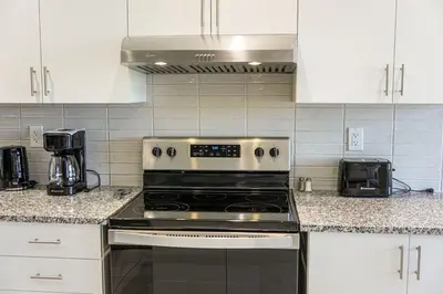 a kitchen with a stove and white cabinets at Spacious 3BR Townhome Near Casino & Thermea Spa in Ajax