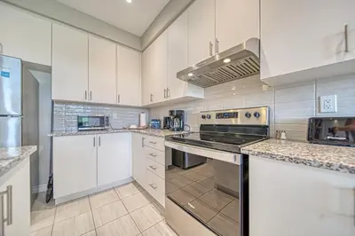 a kitchen with white cabinets and a stove top oven at Spacious 3BR Townhome Near Casino & Thermea Spa in Ajax