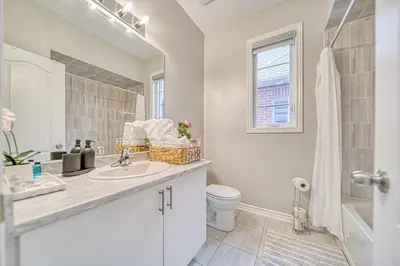 a white bathroom with a sink and a toilet at Spacious 3BR Townhome Near Casino & Thermea Spa in Ajax