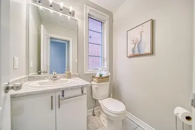 a white bathroom with a toilet and a sink at Spacious 3BR Townhome Near Casino & Thermea Spa in Ajax