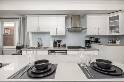 a kitchen with white cabinets and black plates and glasses at Entire Unit - Steps From History - 5 Mins To Beaches in Toronto