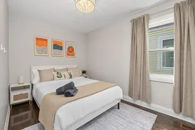 a white bedroom with a bed and a window at Entire Unit - Steps From History - 5 Mins To Beaches in Toronto