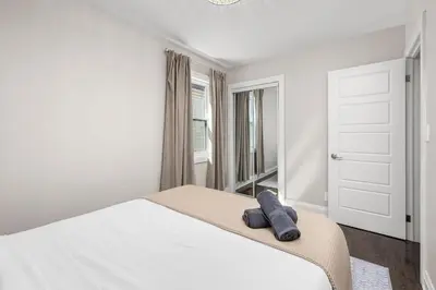 a white bedroom with a bed and a window at Entire Unit - Steps From History - 5 Mins To Beaches in Toronto