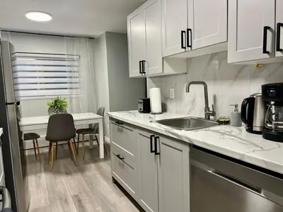 a kitchen with white cabinets and a sink and a table at Modern 2 bedroom, 2 king beds, close to Hwy in Kitchener