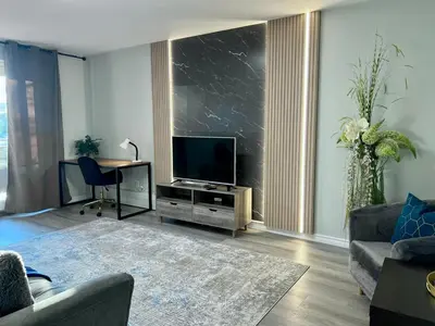 a living room with a flat screen tv and a table at Modern 2 bedroom, 2 king beds, close to Hwy in Kitchener