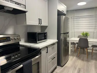 a kitchen with a stainless steel refrigerator and a table at Modern 2 bedroom, 2 king beds, close to Hwy in Kitchener