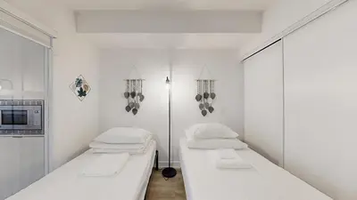 two beds in a room with white walls at Cozy 2 Bdrm 2 Bath Entire Suite - Centre Hamilton in Hamilton
