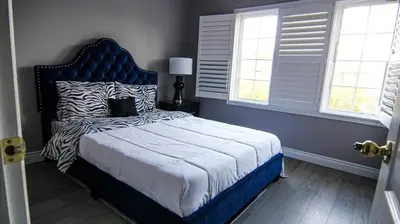 a bedroom with a bed with a blue headboard and windows at Spacious 5br Home W Parking In Mississauga in Mississauga