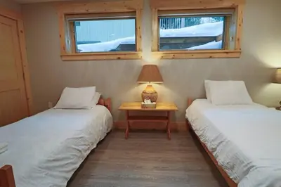 two beds in a room with a table and two windows at Waterfront 3 Bedroom Home in Port McNicoll