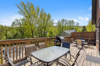 a deck with tables and chairs and a grill at 8 BR Luxury Swiss Style Chalet w Hot Tub in Blue Mountains