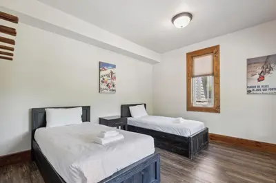 two beds in a room with white walls and wooden floors at 8 BR Luxury Swiss Style Chalet w Hot Tub in Blue Mountains