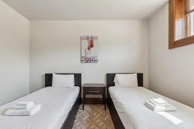 two beds in a room with white sheets at 8 BR Luxury Swiss Style Chalet w Hot Tub in Blue Mountains