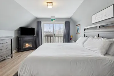 a bedroom with a white bed and a fireplace at The 19th Hole at Blue with Hot Tub in Blue Mountains