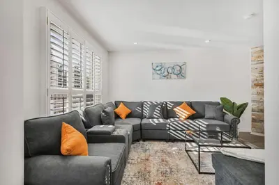 a living room with a gray couch and orange pillows at Luxe 4BR Retreat w Heated Pool Hot Tub and BBQ in Whitby