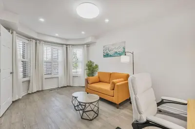 a living room with a couch and a chair at Luxe 4BR Retreat w Heated Pool Hot Tub and BBQ in Whitby